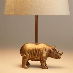 a gold rhinoceros lamp with a white shade on it's head and neck