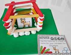 a wooden toy house sitting on top of a green mat next to a printable book