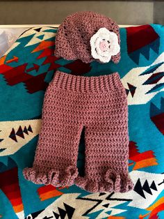 a crocheted baby outfit with a flower sits on top of a colorful blanket