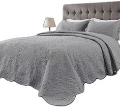 a bed with a gray bedspread and pillows