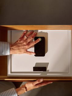 two hands reaching for an electronic device on a table