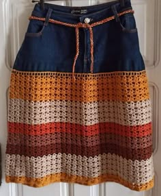 a crocheted skirt hanging on a door with an orange, yellow and brown stripe