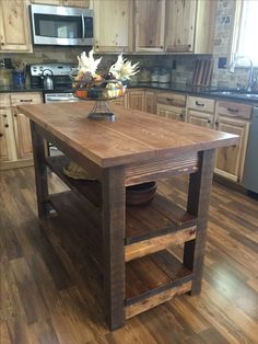 a kitchen island made out of wood in the middle of a wooden flooring area