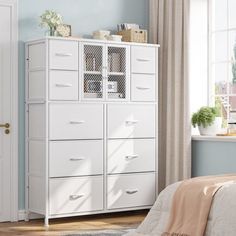 a bedroom scene with focus on the bed and white dresser unit in the foreground