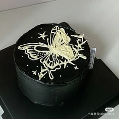 a black cake with white icing and a butterfly on it