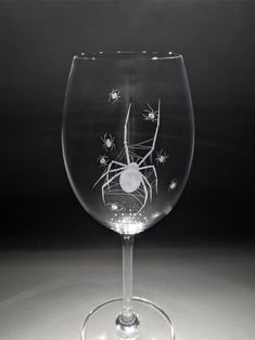 a wine glass with a spider drawn on the side and some flies flying around it