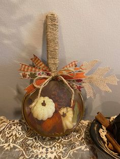 a glass jar filled with pumpkins on top of a lace tablecloth covered table