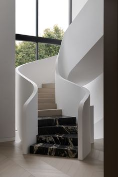 a spiral staircase with marble steps leading up to the second floor