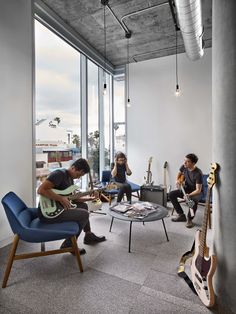 a living room filled with furniture and lots of glass windows next to a guitar on top of a coffee table