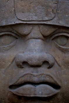 the face of an ancient statue is shown in close up, with eyes wide open