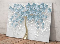 a painting with blue flowers on it in front of a white wall and wooden floor