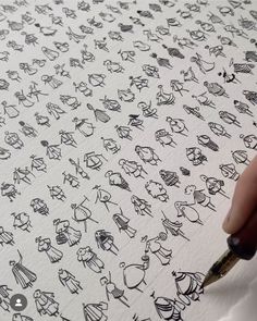 someone is writing on paper with black ink and some drawings are drawn in the background