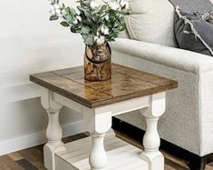 a vase with flowers sitting on top of a wooden table next to a white couch