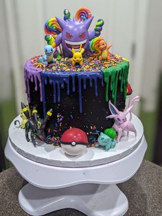 a birthday cake decorated with sprinkles and pokemon figurines on top