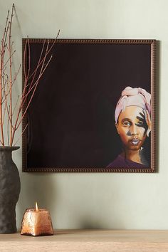 a painting hangs on the wall next to a candle