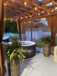 an outdoor hot tub surrounded by potted plants and lights on the ceiling above it