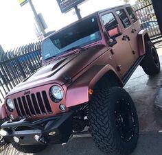 a pink jeep parked in front of a fence