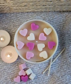 a bowl filled with marshmallows next to two candles