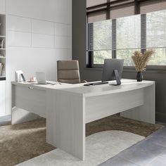 an office desk with a laptop on it in front of a bookcase and window