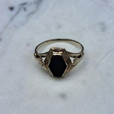 This Art Deco 10k Gold Onyx Ring is a vintage-inspired accessory featuring a polished black onyx gemstone set in a 10-karat gold band. The design reflects the geometric elegance of the Art Deco era, characterized by clean lines, bold shapes, and intricate detailing. This ring combines classic sophistication with striking contrasts, making it an eye-catching piece suitable for both formal and casual occasions. Gold Onyx Ring, Onyx Engagement Ring, Black Engagement Ring, Deco Ring, Onyx Gemstone, Art Deco Era, Onyx Ring, Gold Band, 10k Gold