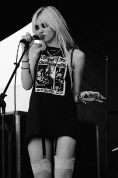 a woman standing on top of a stage holding a microphone in her hand and wearing thigh high stockings