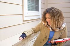 a woman with curly hair is holding something in her hand and standing on the porch