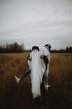 two people dressed as ghost hugging in a field