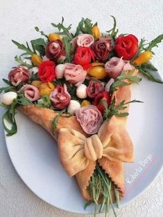 a piece of pizza decorated with flowers on top of a white plate and tied in a bow