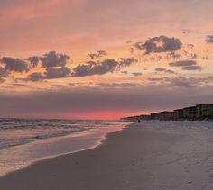 the sun is setting at the beach with clouds in the sky