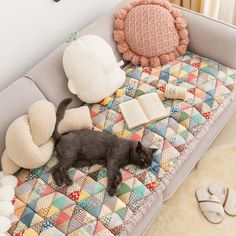 a black cat laying on top of a bed covered in pillows and blankets next to a stuffed animal