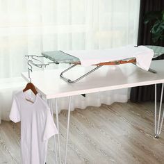 an ironing board with clothes on it and a t - shirt hanging out to dry