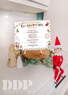 an elf is sitting on top of the counter next to a sign that says, santa's workshop celebration