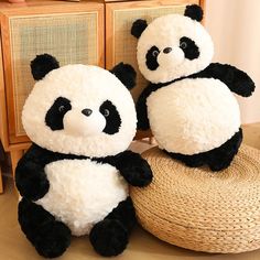 two stuffed panda bears sitting next to each other on top of a wooden floor near a wicker basket