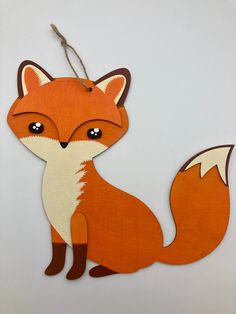 a wooden cutout of a fox sitting on top of a white table next to a string