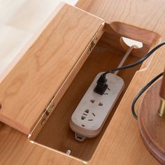 an electrical outlet in the middle of a wooden box with a light plugged into it