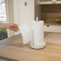 a person holding a roll of toilet paper on top of a wooden counter in a kitchen