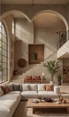 a living room filled with lots of furniture next to a stair case covered in windows