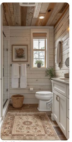 a bathroom with wood paneling and white fixtures, including a rug on the floor