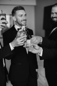 three men in tuxedos are toasting each other while holding wine glasses and bottles