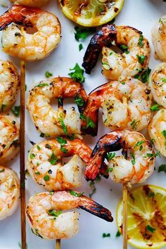 grilled shrimp skewers with lemon wedges and parsley on a white plate