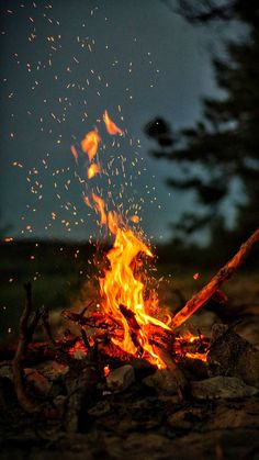 the fire is burning brightly in the dark night sky, with lots of sparks coming from it