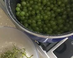 green grapes are being cooked in a pot on the stove top next to a white plate