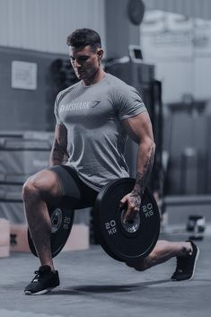 a man doing squats with a barbell in his hand and holding a weight plate