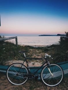 a bicycle parked on the beach next to a boat