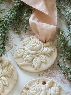 three decorated cookies sitting on top of a table next to a pink napkin and flowers