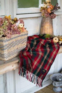 two baskets filled with flowers sitting on top of a wooden shelf next to a window