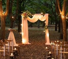 an outdoor wedding set up in the woods with candles and draping draped over it