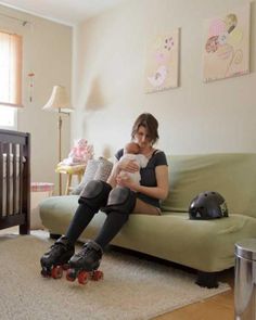 a woman sitting on a couch holding a baby in her arms and roller skates