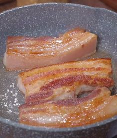 two pieces of bacon cooking in a frying pan