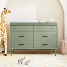 a toy giraffe standing next to a dresser in a room with white walls